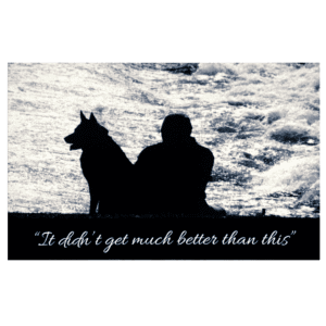 A man and his dog sitting in the grass.